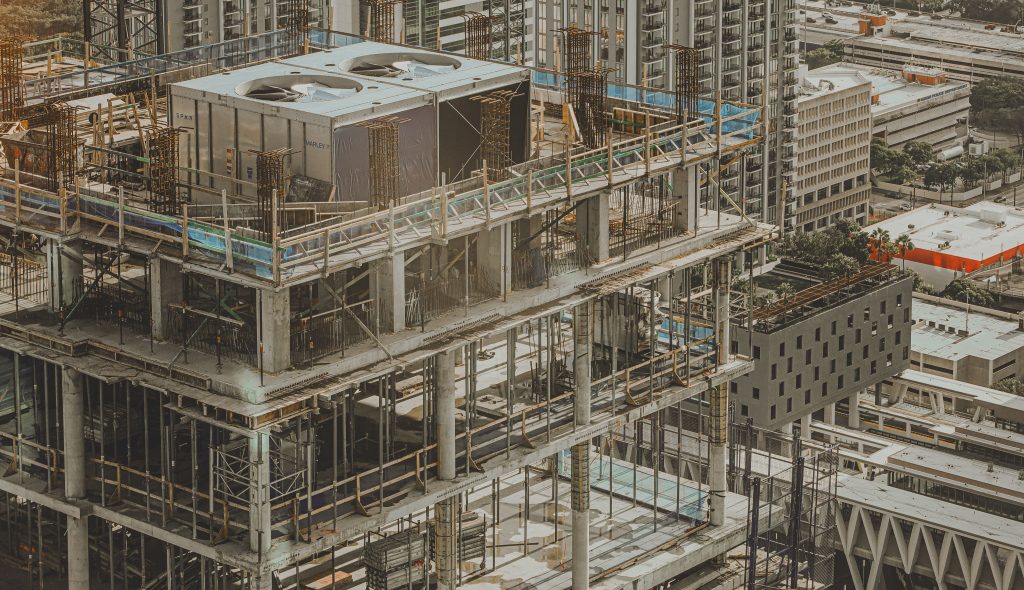 Aerial view of a high-rise building under construction in a bustling city environment.